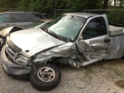 Wrecked Ford F150 with significant damage down the drivers side from getting T-boned