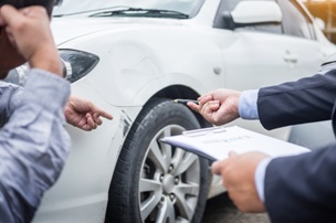 insurance adjuster inspecting car accident damage 