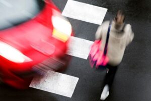 "red car about to hit pedestrian in crosswalk"
