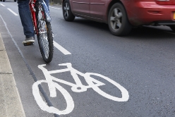 A Bicyclist Riding Alongside a Red Car