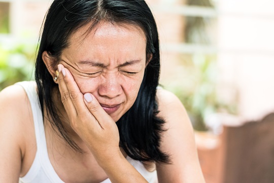 woman holding her face with jaw pain