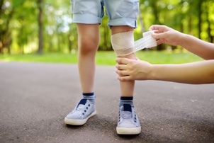 child with knee injury getting medical bandage 