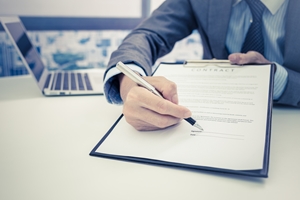 Man holding out clipboard with paper to sign