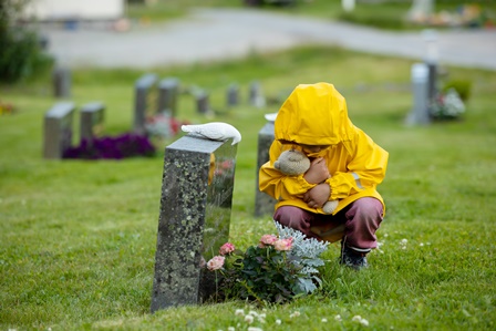 child-in-raincoat-by-grave