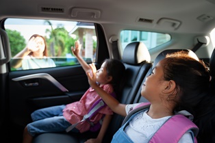 children-backseat-car-waving-goodbye