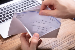 person opening settlement check over laptop keyboard
