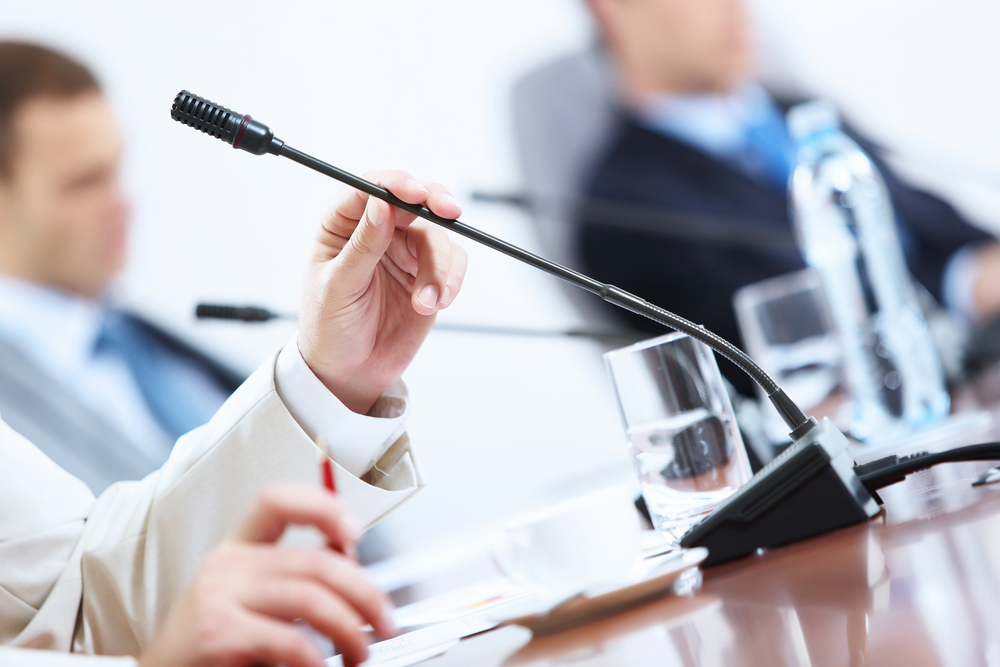 close-up of man holding microphone at conference table