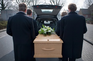 Pallbearers putting a casket in a hearse at a funeral due to wrongful death